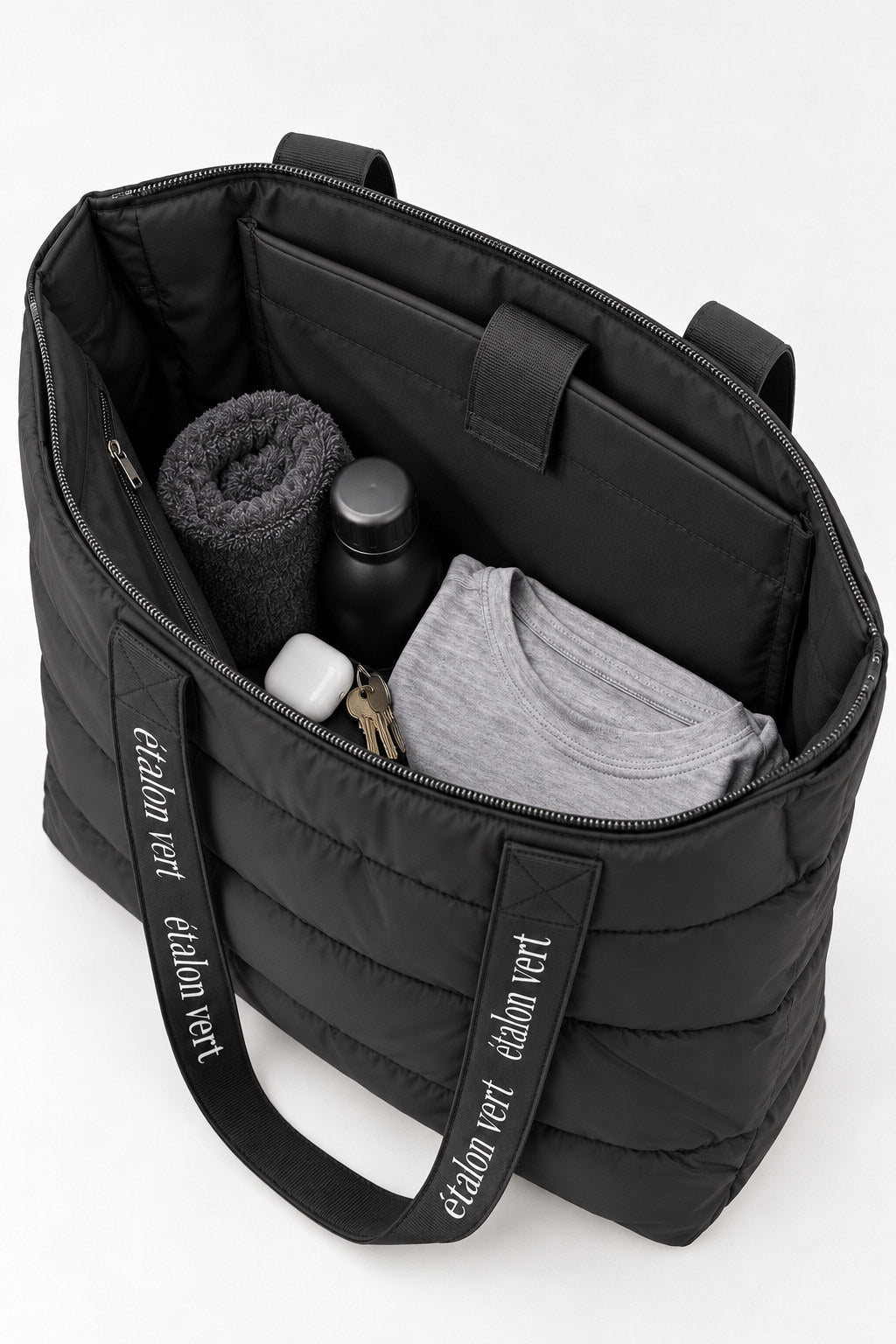 Puffer Bag Black – geöffnete Tasche mit beispielhafter Gym-Füllung aus Handtuch, Flasche und Kleidung
