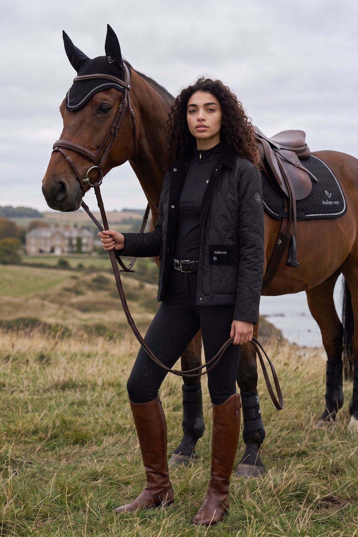 étalon vert Baloubet Heritage Jacket in Schwarz – Jacke am Model neben einem Pferd