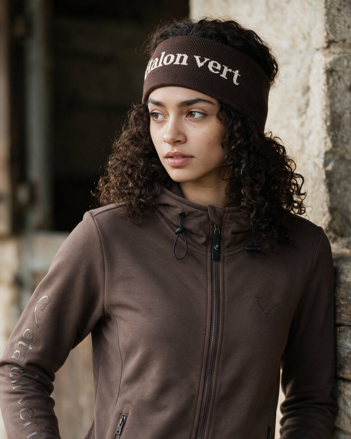 Don Carlos 2.0 Stirnband chocolate-brown am étalon vert Model Maya, mit passendem eigenen Winteroberteil – KI-Produktvisualisierung; Farbton vorläufig