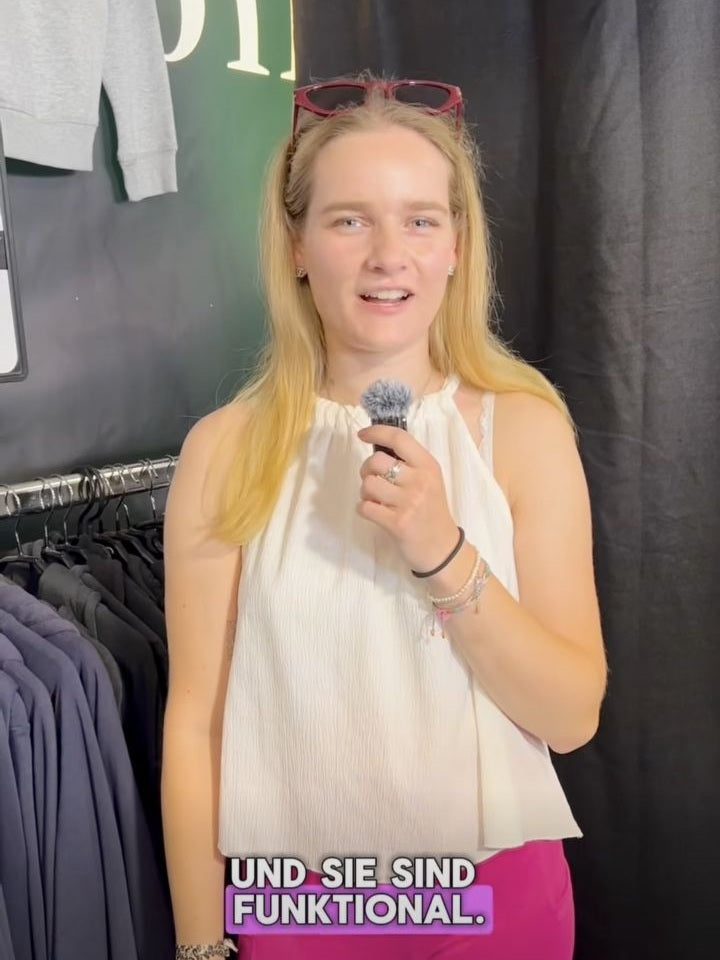 Besucherin mit Mikrofon im Original-Kundeninterview in Aachen, helles Oberteil und pinke Reithose