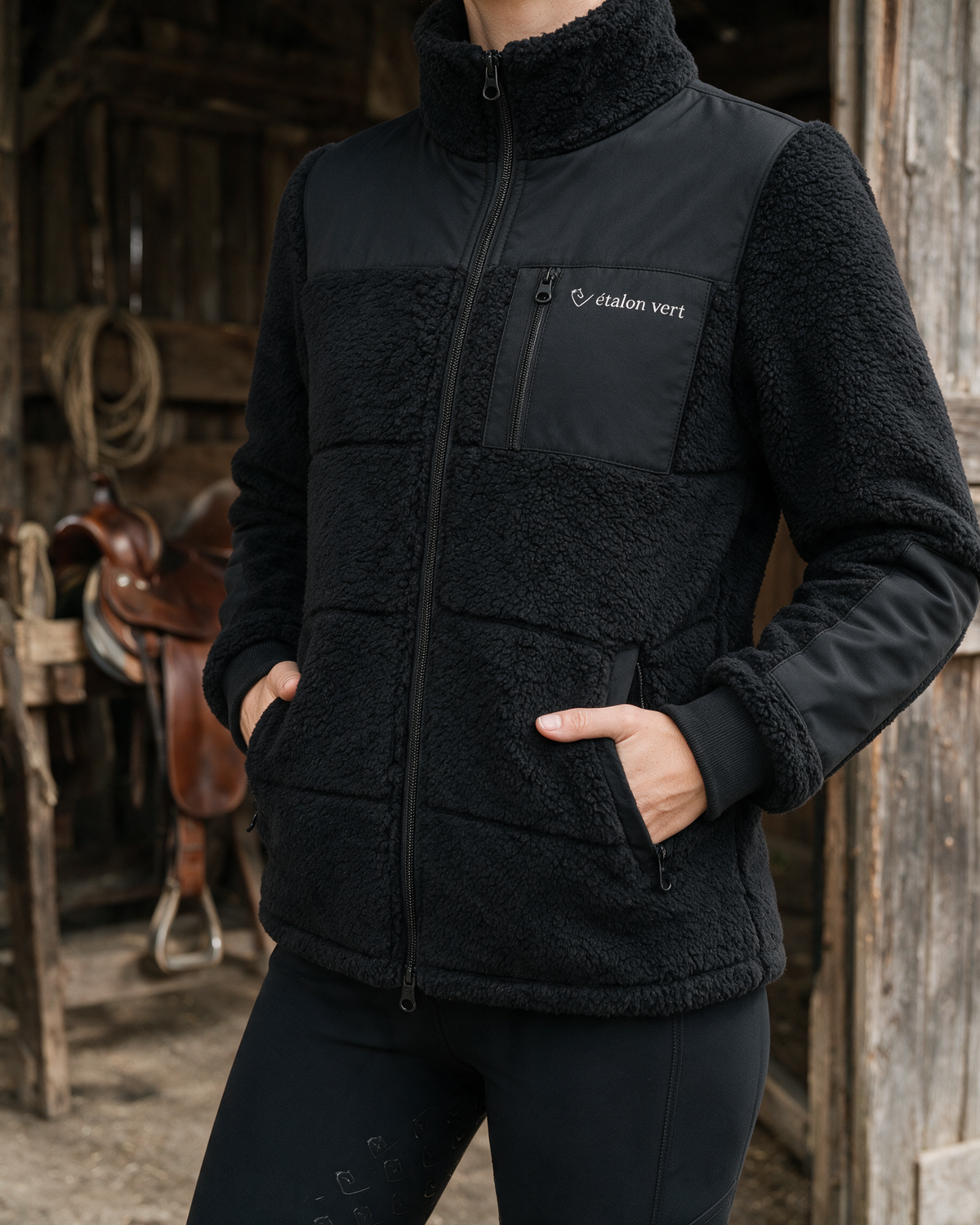Valegro Teddyjacke Schwarz am Model, geschlossene Front mit Händen in den Taschen
